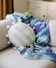 a blue and white pillow sitting on top of a couch