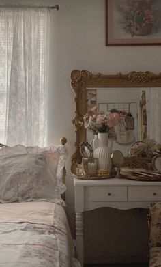 a white bed sitting under a window next to a dresser with flowers on top of it