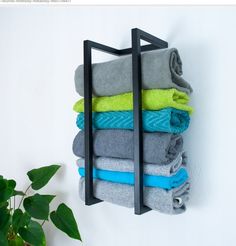 a stack of folded towels hanging on a wall next to a potted green plant