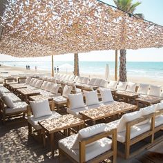 tables and chairs are set up under an umbrella on the beach