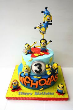 a three tiered birthday cake with minion characters on it and the number 3