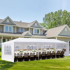 a large tent set up in front of a house with tables and chairs on the lawn