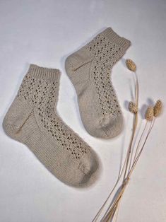 two pairs of knitted socks sitting on top of a table next to dried flowers