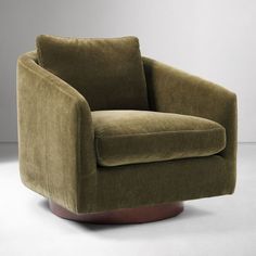 a green chair sitting on top of a white floor next to a gray wall with a round wooden base