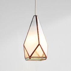 a light hanging from a ceiling with a white wall in the background and a brown stained glass shade