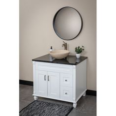 a white sink sitting under a round mirror on top of a counter next to a rug