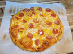 a pepperoni and pineapple pizza sitting on top of a piece of parchment paper