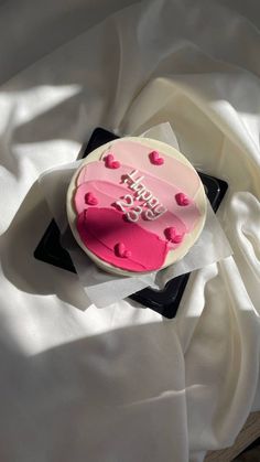 a cake with pink frosting and hearts on it sitting on top of a white sheet