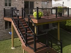 a deck with railings and planters on it in front of a brick building