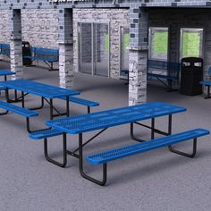 several blue picnic tables in front of a brick building