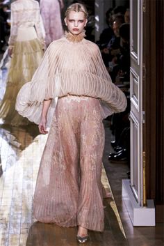 a model walks down the runway in a pink dress