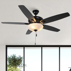 a ceiling fan in a living room with large windows