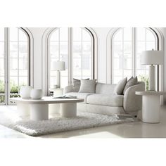 a living room filled with white furniture and large windowed windows on the side of it