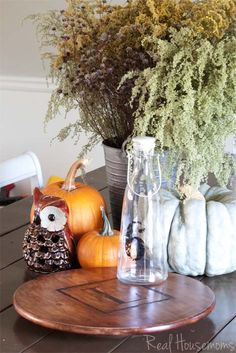 pumpkins and gourds are sitting on a table in front of a vase