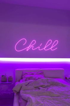 a bed in a room with purple lighting and a neon sign on the wall above it