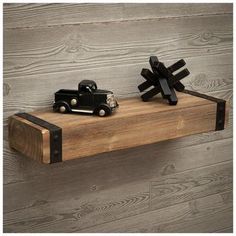 a wooden shelf with two black toy cars on it and one is made out of wood