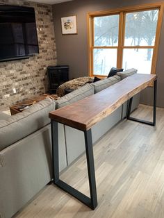 a living room with couches and a wooden table in front of a tv mounted on the wall