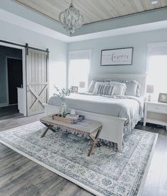 a large bed sitting on top of a wooden floor next to a white dresser and chair