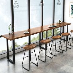 a long table with four stools next to it in front of a large window