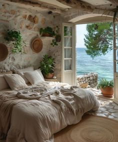 a bedroom with an ocean view is shown in this image, it has a stone wall and large windows