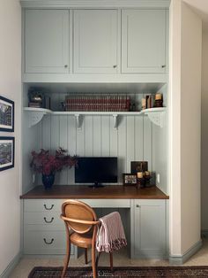 a desk with a computer on top of it next to a chair and bookshelf