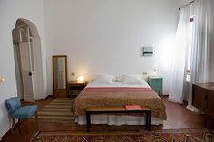 a bed room with a neatly made bed next to a dresser and mirror on the wall