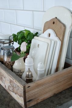 a wooden tray filled with white dishes and utensils on top of a counter