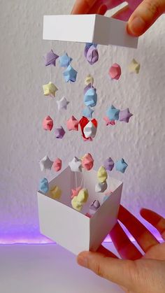 a hand holding a white box with some little stars hanging from it's sides