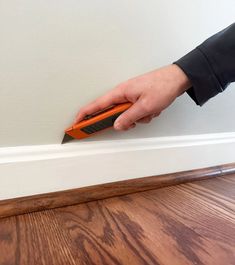 a person is holding an orange object in their hand on the edge of a door