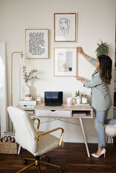 a woman standing in front of a desk with a laptop on it