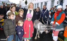 a group of people standing next to each other in front of a small animal on a street