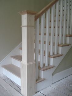 a wooden stair case next to a white banister