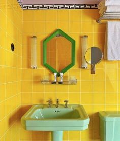 a bathroom with yellow tiles and green sink in the corner, along with two mirrors on the wall