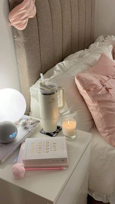 a bed with pink pillows, books and a lamp on top of the headboard