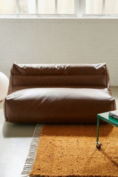 a brown leather couch sitting on top of a rug