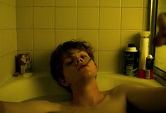 a young man laying in a bathtub with his eyes closed