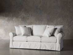 a white couch sitting in front of a wall with lots of pillows on top of it