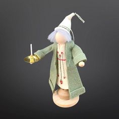 a wooden doll holding a candle and wearing a green coat with white hair on it's head