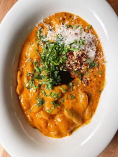 a white bowl filled with food and garnished with parmesan sprinkles