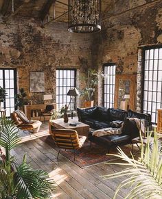 a living room filled with lots of furniture next to tall windows and potted plants