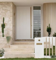 a white door and some plants in front of a house