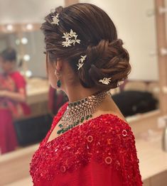 a woman in a red dress is looking at herself in the mirror with her hair pulled back