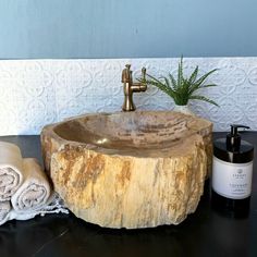 a wooden sink sitting on top of a table next to towels and a potted plant