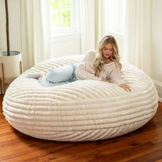 a woman laying on top of a large round bed