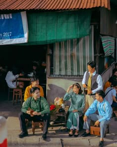 a group of people sitting around each other in front of a building