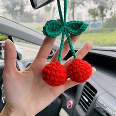 a hand holding two red pom - poms in front of a steering wheel