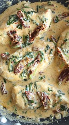 a skillet filled with chicken and spinach covered in gravy on top of a table