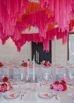 pink and orange streamers hang from the ceiling above a table set for a party