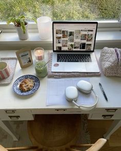 a laptop computer sitting on top of a desk next to a cup and saucer