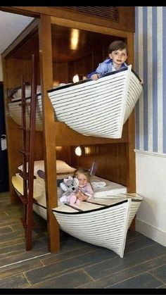 two children are sitting on the bottom bunk of a boat bed in a room with striped walls